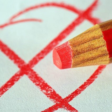Ein roter Buntstift macht ein rotes Kreuz in einem roten Kreis
