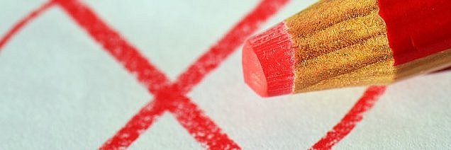 Ein roter Buntstift macht ein rotes Kreuz in einem roten Kreis