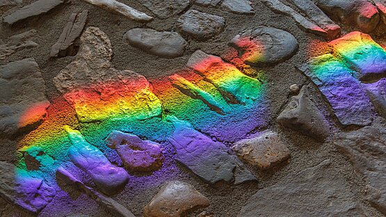 Regenbogenartige Lichtreflexion auf dunklem Steinboden